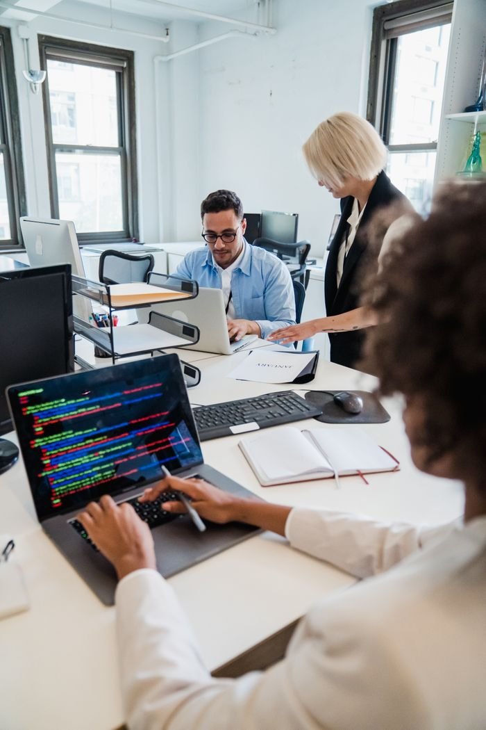 why-choose-us Team of professionals collaborating in a modern office, focused on coding and project management.